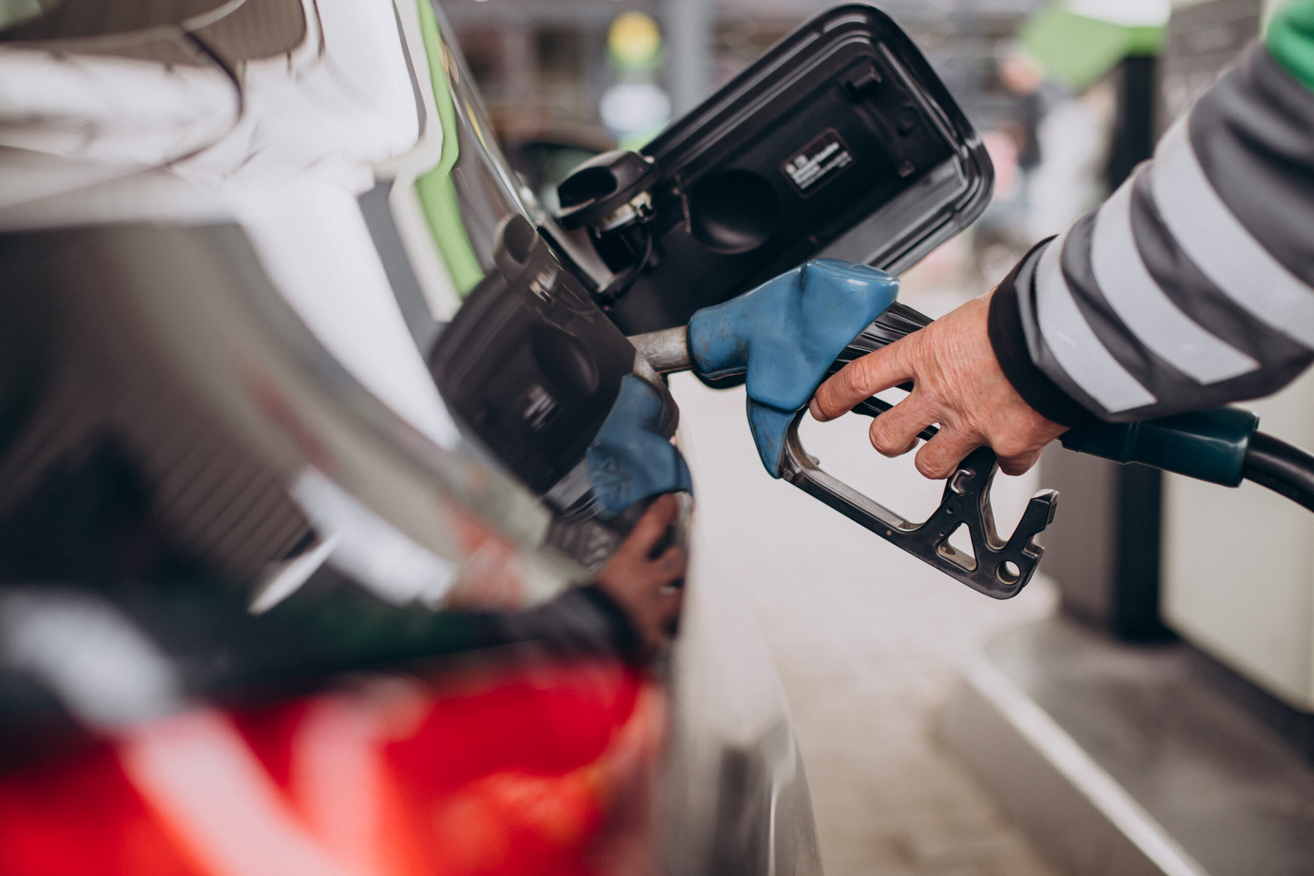 Persona cargando combustible en un automóvil en una estación de servicio, ilustrando buenas prácticas para reducir el consumo de bencina.